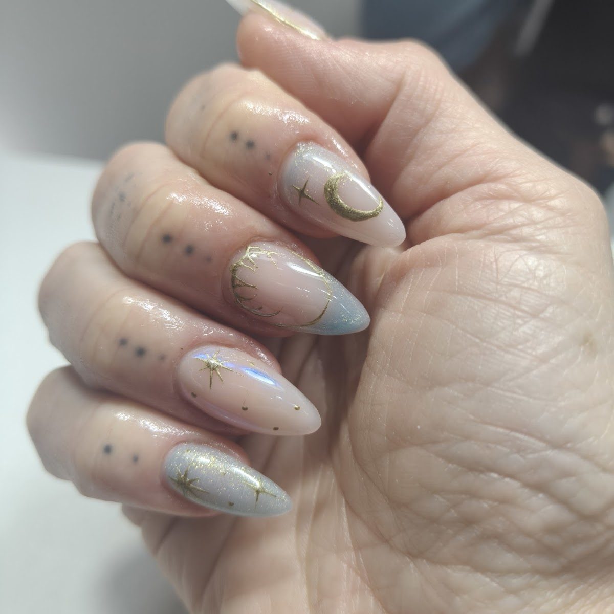 Uñas almendradas en tono nude con detalles dorados pintados a mano